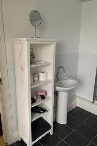a bathroom with a sink and a white cabinet with a mirror at Cosy cottage in picturesque Snowdonia with stunning views of the Moelwyn mountains in Blaenau-Ffestiniog