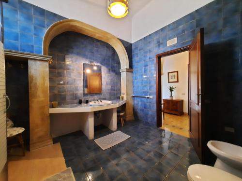 a bathroom with a sink and a blue tiled wall at Villa del Commendatore Sirugo in Avola