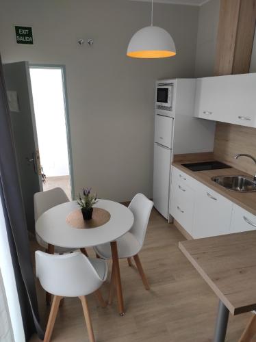 a kitchen with a table and white chairs and a table at Apartamentos turísticos CASA de los BALCONES in Chipiona