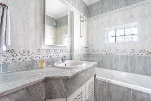 a white bathroom with a sink and a bath tub at Villa Lemos by HelloVacations in Albufeira