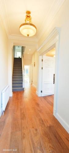 an empty hallway with a staircase and a chandelier at Marigold Villa in Harrow