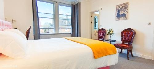 a bedroom with a white bed and two chairs at Marigold Villa in Harrow