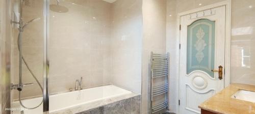 a bathroom with a shower and a tub and a sink at Marigold Villa in Harrow
