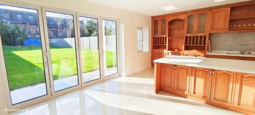 una cocina con armarios de madera y una gran ventana en Marigold Villa, en Harrow