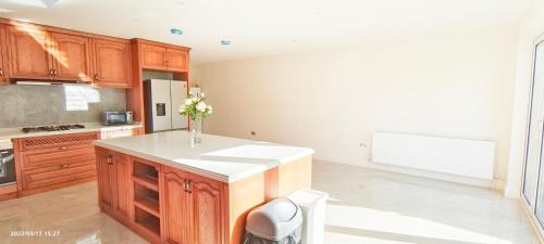 a kitchen with wooden cabinets and a vase of flowers on a counter at Marigold Villa in Harrow