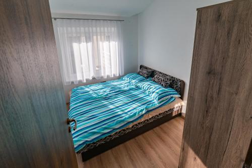 a bedroom with a bed with a striped comforter at Golden Beach Apartments Siófok in Siófok