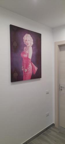 une peinture d'une femme en robe rose sur un mur dans l'établissement B&B SKY LINE, à Crotone