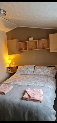 a bedroom with a bed with two towels on it at Carmels Caravan Borwick Lakes in Carnforth