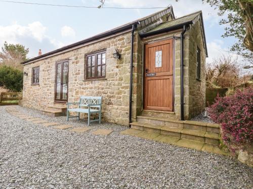a stone house with a wooden door and a bench at Brocks Barn in Lanlivery