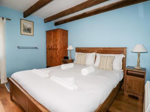 um quarto com uma cama grande e lençóis brancos em 4 Mowhay Cottages em Saint Goran