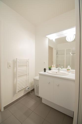 une salle de bain blanche avec un lavabo et un miroir dans l'établissement Le Paisible T2-48m2-Proche Val d'Europe-Disney, à Montévrain