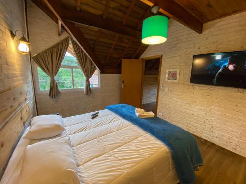 um quarto com uma cama grande e uma televisão na parede em Pousada Viviê CENTRAL em Monte Verde