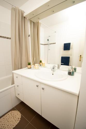 une salle de bain blanche avec un lavabo et un miroir dans l'établissement Le Délicieux T2-42m2-Disney, à Montévrain