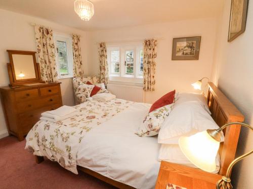 een slaapkamer met een bed en een lamp en twee ramen bij Eastburn Cottage in West Burton