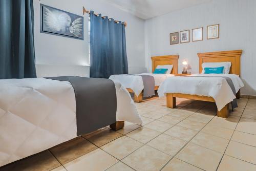 a room with three beds with blue and white sheets at Ayenda Posada San Nicolas in Guadalajara