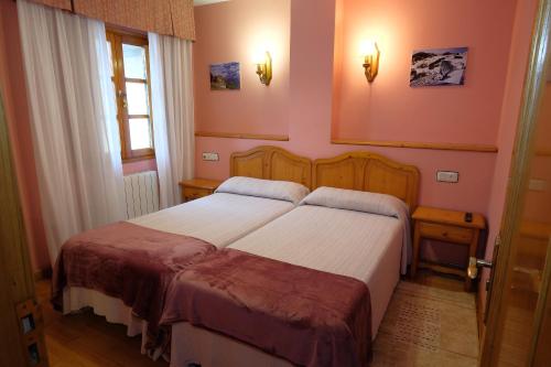 two beds in a room with pink walls at Hotel Restaurante Casa Manolo in Páramo