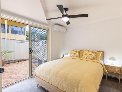 a bedroom with a yellow bed and a balcony at Baia Villa air con WiFi and views of Fingal Beach in Fingal Bay