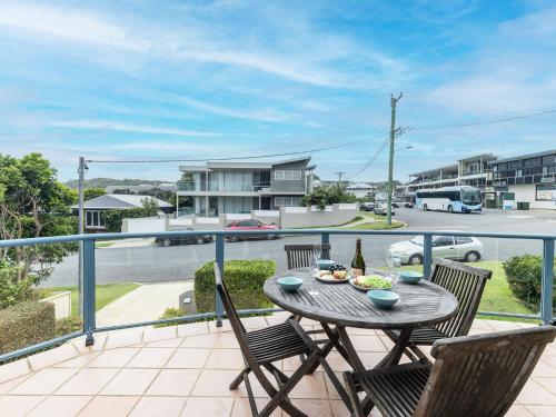 a patio with a table and chairs on a balcony at Baia Villa air con WiFi and views of Fingal Beach in Fingal Bay