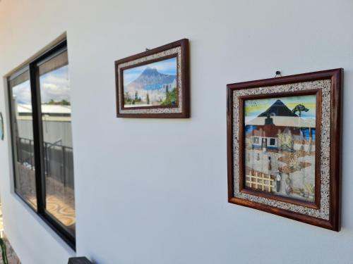 two framed pictures hanging on a wall next to windows at Apartamentos Ave del Paraíso in Alajuela City