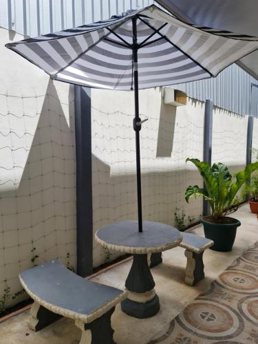 a table with an umbrella and a bench at Apartamentos Ave del Paraíso in Alajuela City