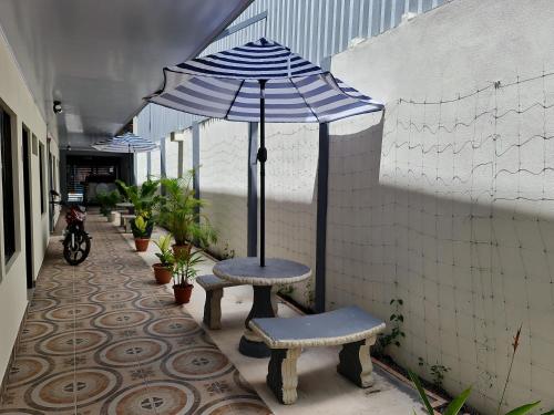 a patio with two benches and an umbrella at Apartamentos Ave del Paraíso in Alajuela City