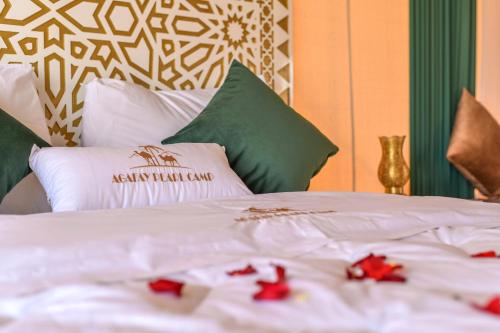 a white bed with red flowers on top of it at Agafay Pearl Camp Marrakech in Marrakech