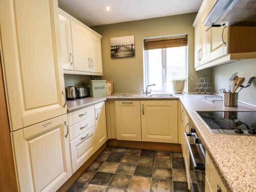 a kitchen with white cabinets and a tile floor at Ty'r Heulwen in Aberdyfi