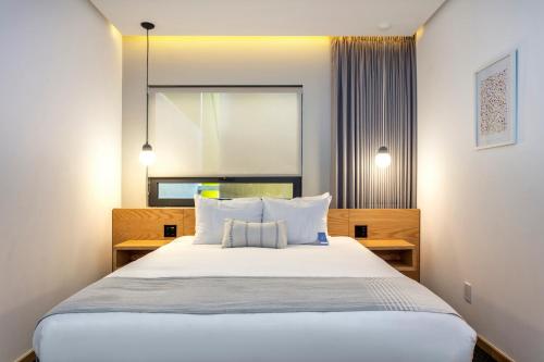 a bedroom with a bed with white sheets and pillows at V65 Mx in Mexico City