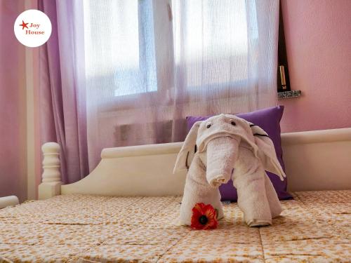 un elefante disecado sentado en una cama con una flor en Joy House, en Porto Torres