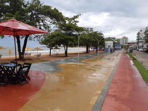 una calle con una mesa y una sombrilla y una playa en Linda casa 3 quartos Castelhanos ES en Anchieta