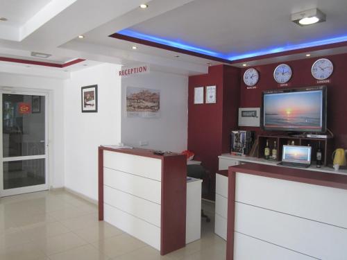 a waiting room with a tv and clocks on the wall at Family Hotel Magnolia in Balchik