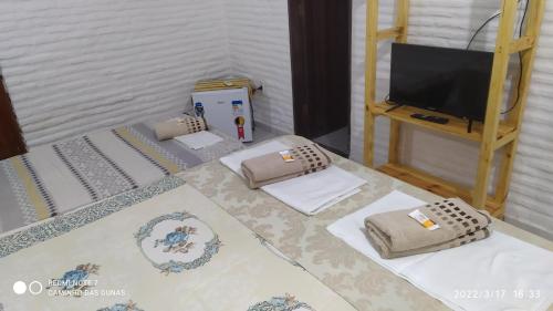 two beds with pillows and a television in a room at Pousada Caminho das Dunas in Cumbuco