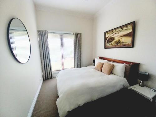 a bedroom with a large bed and a mirror at Ocean Aspect and Central to CBD - CoSheirm Apartments On Merri in Warrnambool