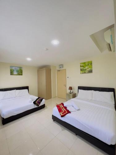 two beds in a room with white walls at Noor Hotel Kangar in Kangar