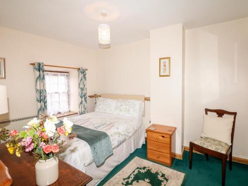 a bedroom with a bed and a table and a chair at Swift Cottage in Mawgan in Meneage
