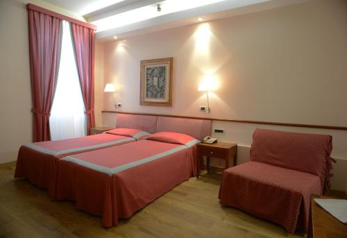 una camera d'albergo con due letti e una sedia di Hotel Colombia a Trieste