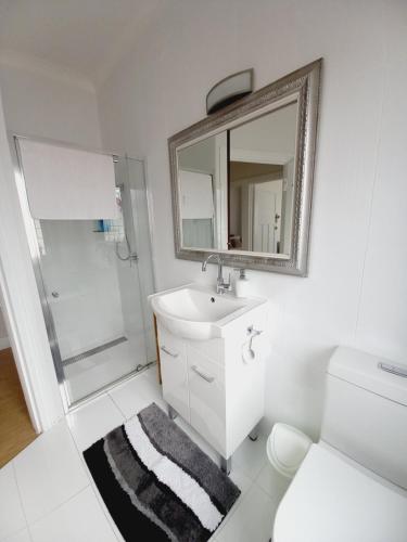 W łazience znajduje się umywalka, prysznic i lustro. w obiekcie Ocean Aspect and Central to CBD - CoSheirm Apartments On Merri w mieście Warrnambool