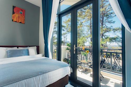 ダラットにあるBạch Trà Villaのベッドルーム(ベッド1台付)、バルコニーが備わります。