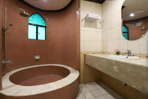 a bathroom with a large tub and a sink at Camelot Hotel in Manila