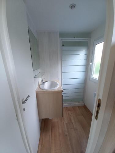 a bathroom with a sink and a door with a window at Mobil home 3 chambres camping 4 étoiles in Saint-Martin-Plage
