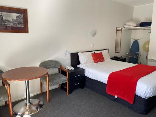 Habitación de hotel con cama, mesa y silla en Ascot Motor Lodge, en Wellington