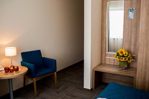 a room with a blue chair and a table and a window at Hotel Meeting in Toruń