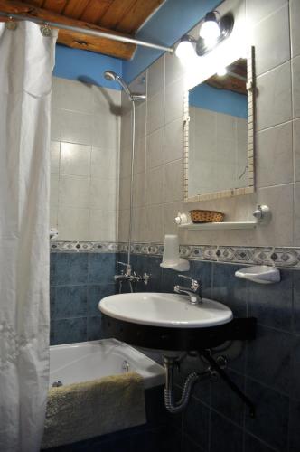 a bathroom with a sink and a mirror and a tub at Carpe Diem Cabañas & Suites in El Bolsón