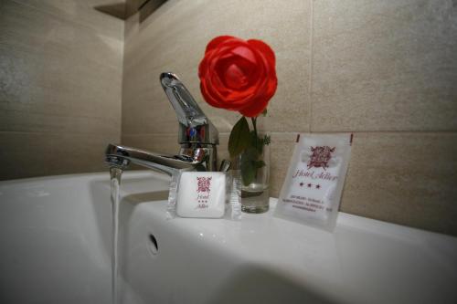 una rosa rossa seduta sopra un lavandino di Hotel Adler a Milano