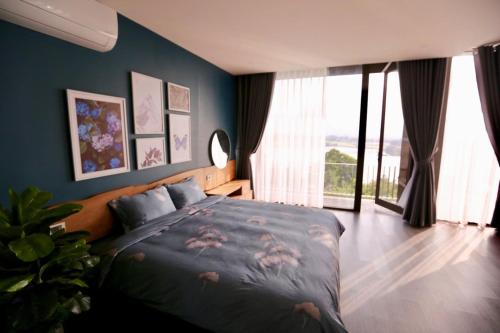 a bedroom with a bed with a blue wall at The Luciola Tam Đảo - Venue Travel in Vĩnh Phúc
