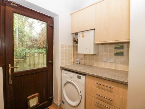 baño con lavadora y ventana en The Skilling, en Bridport