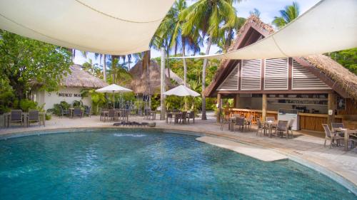 a pool at a resort with tables and chairs at Castaway Island, Fiji in Castaway Island