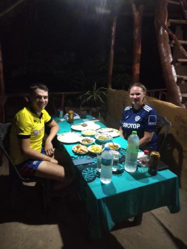 two men sitting at a table with food on it at Relax Nature Villa in Sigiriya