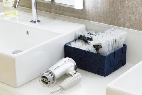 a bathroom sink with a blow dryer and a box of soap at karaksa hotel Sapporo in Sapporo