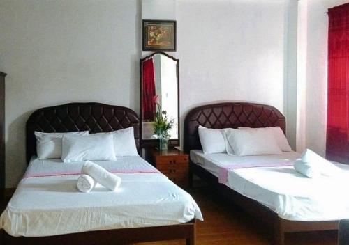 two beds in a hotel room with white sheets at RedDoorz at RHR Tourist Inn Canlaon in Kabankalan